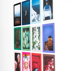 Puede incluir: Una colección de fotografías enmarcadas con varias imágenes, incluyendo un velero, un bosque, un edificio y una persona con uniforme de marinero. Los marcos tienen bordes de diferentes colores, como negro, azul, verde y rosa.