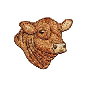 May include: Embroidered patch featuring a detailed brown cow head. The patch showcases intricate stitching, highlighting the cow's features, including its eyes, ears, and muzzle. The design is set against a white background, emphasizing the patch's details. Ideal for adding to clothing or accessories.