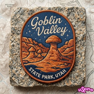 May include: An oval embroidered patch featuring a dark blue night sky with white stars above a landscape of orange rock formations. The text reads Goblin Valley in script and STATE PARK, UTAH in block letters, all bordered by a copper-colored edge.
