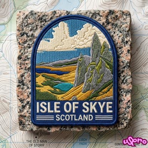May include: An embroidered patch featuring a landscape of the Isle of Skye, Scotland, with jagged grey rock formations, golden hills, a blue lake, and white clouds against a blue sky. The text ISLE OF SKYE SCOTLAND is stitched in white.
