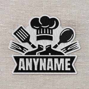 May include: Embroidered patch featuring a chef's hat, chef's coat, and cooking utensils. The patch is black and white with the word "ANYNAME" in a banner. The design is on a textured, light beige background.
