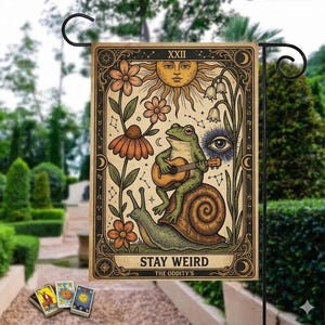 Puede incluir: Bandera de jardín con un diseño caprichoso. Muestra una rana tocando la guitarra sobre un caracol, rodeada de flores y símbolos celestiales. Incluye el texto "STAY WEIRD" y un estilo vintage.
