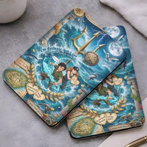 May include: Two phone cases with a fantasy illustration featuring characters, a trident, and ocean waves. The cases have text that reads "I'm dyslexic but I can still spell wack for", "seaweed brain", and "wise girl". The design includes a map and the words "Welcome to New York".