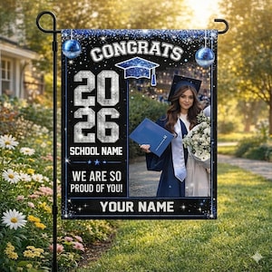 May include: A graduation garden flag with a black background and blue accents. The flag reads "CONGRATS 2026" and "WE ARE SO PROUD OF YOU!" A photo of a graduate in a cap and gown is featured. The flag is displayed on a black metal stand.