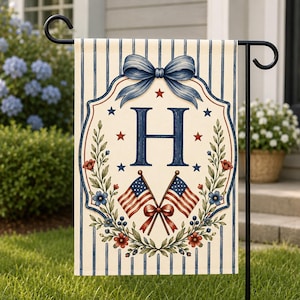 Könnte beinhalten: Eine Gartenflagge mit patriotischem Thema. Die Flagge zeigt einen großen blauen Buchstaben "H", umgeben von einem floralen Kranz, roten Sternen und zwei amerikanischen Flaggen. Oben befindet sich eine blaue Schleife, vor einem Hintergrund aus blau-weißen Streifen.