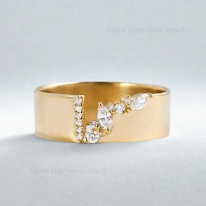 Puede incluir: Un anillo ancho, de color dorado con un diseño moderno. El anillo presenta una fila de pequeños diamantes redondos y un grupo de diamantes talla marquesa. Las palabras "Glow Diamond Jewel" son visibles en la imagen.