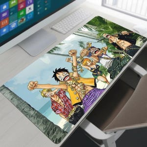 Op de afbeelding: Een rechthoekige muismat met een kleurrijke illustratie van anime-personages op een strand. Het ontwerp toont personages in diverse outfits, tegen een achtergrond van palmbomen en een blauwe lucht. De muismat ligt op een witte bureau.