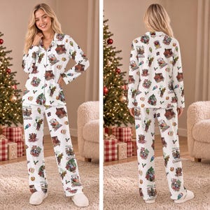 Può includere: Un pigiama bianco a maniche lunghe composto da camicia abbottonata e pantaloni coordinati, caratterizzato da una stampa grafica natalizia ripetuta. Il motivo include varie illustrazioni festive e il testo "Wherever you find love, it feels like Christmas."
