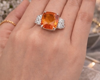 Anillo de diamantes y zafiro naranja en talla cojín, con tres piedras y certificado GIA. Joya nupcial llamativa.