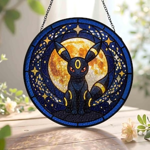 May include: Round stained glass panel featuring a black Umbreon character with yellow accents, set against a full moon backdrop. The panel is framed by a dark blue border with star and celestial designs, and is suspended by a chain.