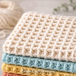 A stacked pile of crocheted dishcloths featuring a textured waffle stitch in cream, blue, and yellow on a light surface.