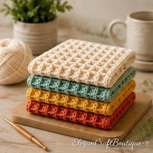 A stack of four colorful waffle stitch crochet dishcloths in cream, teal, yellow, and red rests on a wooden cutting board beside a ball of cream yarn, a wooden crochet hook, and a ceramic mug.