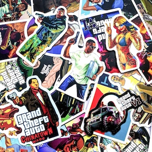 May include: A selection of colourful stickers showcasing characters and logos from the Grand Theft Auto video game series. The stickers feature various characters, vehicles, and game titles, with striking graphics and vivid colours.