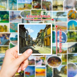 May include: A hand holds a square sticker with a street scene painting, measuring 1.97 inches wide and 1.81 inches tall. The sticker is surrounded by other stickers with landscape art. The street scene features buildings and a person walking.
