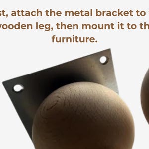 Op de afbeelding: Een lichtgekleurde houten bol bevestigd aan een vierkante metalen montagebeugel met twee zichtbare schroefgaten. De tekst erboven luidt: First, attach the metal bracket to the wooden leg, then mount it to the furniture. Een tweede houten bol is zichtbaar.