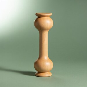 Peut inclure: Un grand support en bois de couleur claire avec une finition lisse et polie. L'objet présente un design tourné symétrique avec une large section arrondie et bulbeuse à la base et une section arrondie assortie plus petite au sommet.