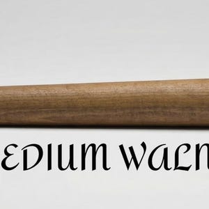 Op de afbeelding: Een cilindervormige houten staaf met een gladde, middelbruine walnootafwerking. De houtnerf is zichtbaar over de gehele lengte van het object. Onder de staaf staat de tekst "MEDIUM WALNUT" gedrukt in een zwart, gestileerd schreeflettertype.