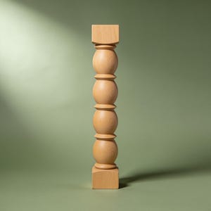 Könnte beinhalten: Ein vertikales Möbelbein aus Holz mit einer hellbraunen, natürlichen Holzmaserung. Das Design besteht aus einem quadratischen Sockel und einem oberen Block mit einer Mittelsäule aus vier gestapelten, glatten, runden Kugeln, die durch Ringe getrennt sind.