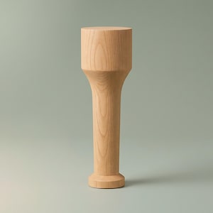 May include: A tall, cylindrical wooden stand featuring a light tan natural wood grain finish. The object has a wider, flat circular top, a slender central column that tapers slightly, and a flared, circular base that provides stability.