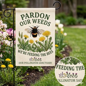 May include: A rectangular garden flag featuring a cream background with the text PARDON OUR WEEDS WE'RE FEEDING THE BEES OUR POLLINATOR SANCTUARY in dark green. The design includes a central bumblebee illustration surrounded by yellow dandelions.