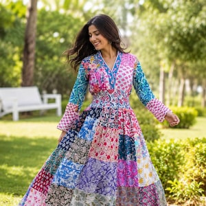 May include: A long-sleeved maxi dress featuring a vibrant patchwork design with various floral and geometric patterns in shades of pink, blue, purple, and white. The dress has a V-neckline, a fitted smocked waist, and a full, flowing skirt.