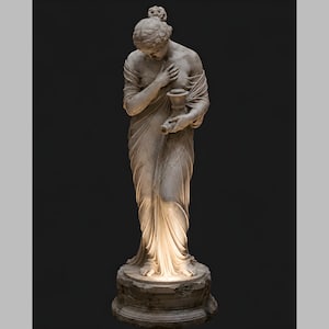 Puede incluir: Una estatua de mármol blanco de cuerpo entero con el cabello recogido en un moño y vestida con una prenda drapeada. La figura sostiene un pequeño recipiente con una mano mientras la otra descansa sobre el pecho, sobre un pedestal circular.