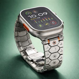 Könnte beinhalten: Eine silberne Smartwatch mit schwarzem Bildschirm, der Zeit, Datum und Aktivitätsdaten anzeigt. Die Uhr hat einen orangefarbenen Akzent und ein Metallarmband. Ein modernes Accessoire.