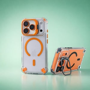 May include: Clear phone case with orange accents. The case features a ring holder and a magnetic charging circle. The design includes orange corner bumpers and camera lens protection. The case is shown in two positions, one upright and one angled.