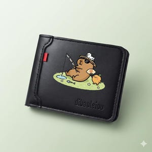 Pode incluir: Carteira preta dobrável com uma ilustração de desenho animado de um urso pescando. O urso usa óculos de sol e um chapéu. A carteira tem um detalhe vermelho e o texto "dibaoleiou".