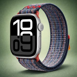 Può includere: Uno smartwatch argentato con un cinturino intrecciato multicolore. Il quadrante mostra i numeri "19:09" in bianco su sfondo nero. Il cinturino presenta dettagli rossi e una chiusura rossa.