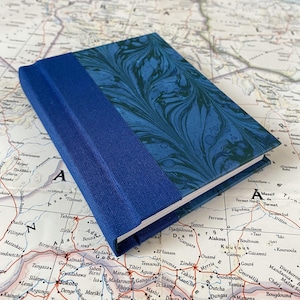 blau und grün marmoriertes Papier mit blauem Buchrücken und leeren Innenseiten