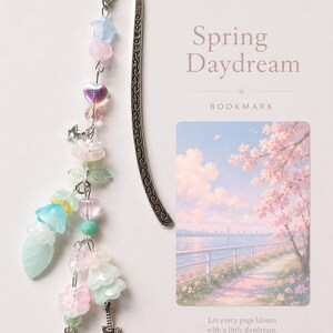 May include: A silver metal bookmark with a curved top and an intricate scroll pattern. A beaded charm hangs from the top, featuring pastel-colored star, heart, flower, and leaf beads, along with small silver guitar and shooting star charms.