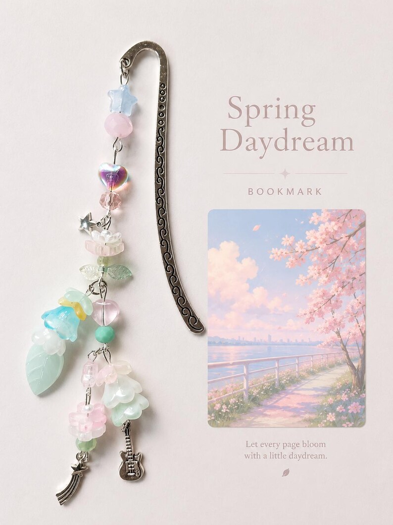 May include: A silver metal bookmark with a curved top and an intricate scroll pattern. A beaded charm hangs from the top, featuring pastel-colored star, heart, flower, and leaf beads, along with small silver guitar and shooting star charms.