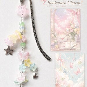 May include: A silver metal hook bookmark adorned with a dangling chain of pastel-colored beads, including pink stars, yellow flowers, a butterfly, and a silver charm engraved with the text Just for you, alongside two rectangular cards with illustrations.