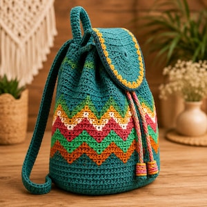 May include: A teal crochet backpack featuring a drawstring closure and a flap with a yellow border. The body displays a multi-colored chevron pattern in orange, green, pink, and white. It includes two shoulder straps and braided drawstrings.