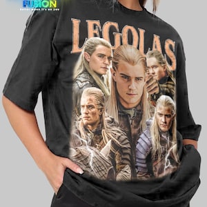 May include: Black unisex t-shirt with a collage of Legolas images from Lord of the Rings and the word "LEGOLAS" in orange. The "Fashion Fusion" logo is in the upper left. The shirt is a unisex design.