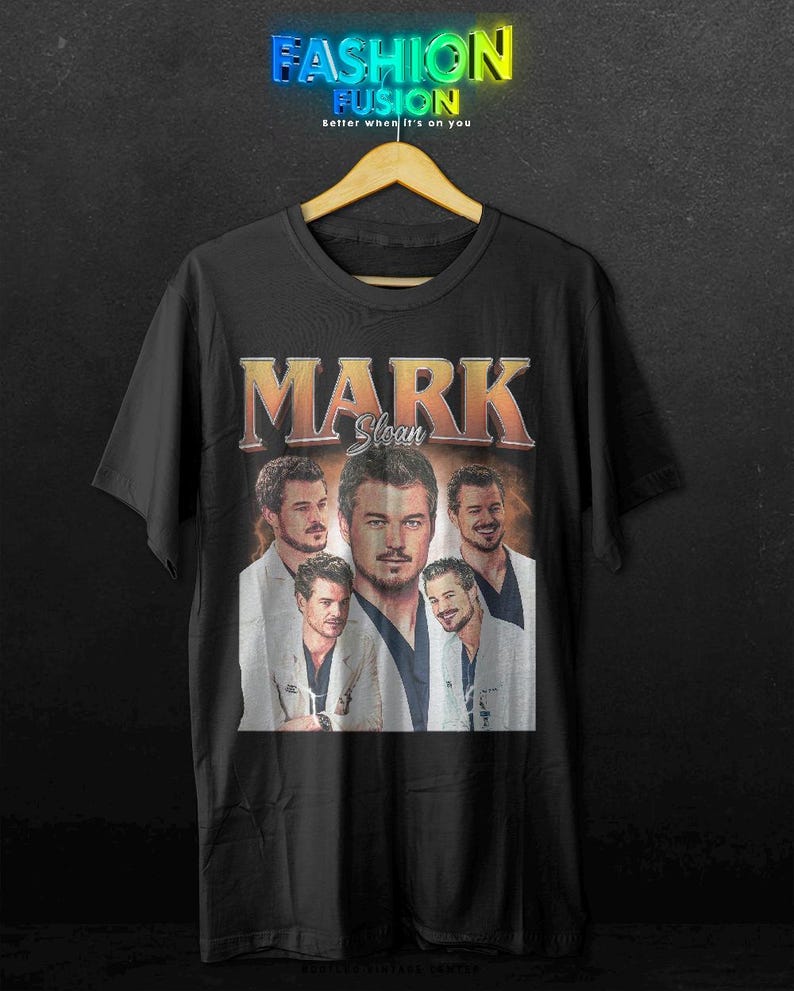 May include: Black t-shirt featuring a collage of images of Mark Sloan with the name "MARK Sloan" in an orange and white vintage style. The shirt has the text "FASHION FUSION" at the top.