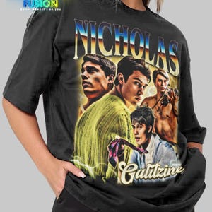 May include: Black unisex t-shirt featuring a vintage-style graphic of four men with the name "Nicholas Galitzine" in a stylized font. The shirt has the "Fashion Fusion" logo in the upper left corner.