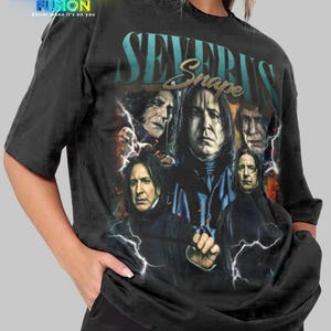 May include: Black t-shirt featuring a graphic of Severus Snape and other characters. The shirt has the text "SEVERUS Snape" in a teal font. The Fashion Fusion logo is in the upper left corner. The shirt is a unisex style.