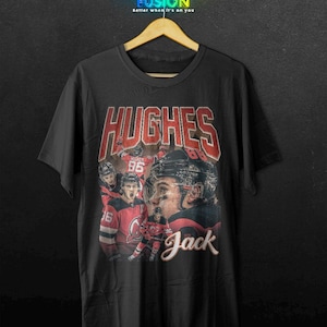 K&ouml;nnte beinhalten: Schwarzes T-Shirt mit einer Hockey-Spieler-Grafik. Das Design zeigt den Namen "HUGHES" in roten Blockbuchstaben, den Spielernamen "Jack" in Schreibschrift und Bilder des Spielers in Aktion. Das Shirt hat auch den Text "Fashion Fusion" oben.