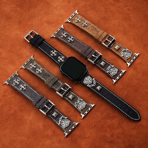 Pode incluir: Cinco pulseiras de relógio de couro em tons de castanho e preto, adornadas com tachas e elementos decorativos prateados. As pulseiras apresentam fechos de fivela e são projetadas para um smartwatch. Estão dispostas sobre uma superfície texturizada castanho-alaranjada.