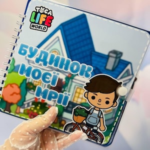 May include: A spiral-bound notebook featuring Toca Life World branding and a cartoon illustration of a house and a character on a bicycle. The cover displays the text "БУДИНОК МОЄЇ МРІЇ" in blue letters. The notebook has a clear plastic cover.