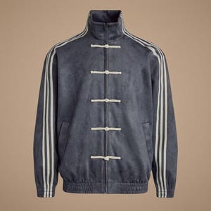 Puede incluir: Chaqueta deportiva azul con rayas blancas en las mangas y cuello alto. La chaqueta tiene cierre de cremallera y cierres de palanca blancos en la parte delantera. Dos bolsillos delanteros.