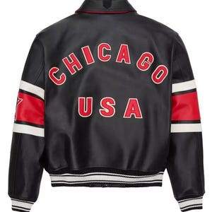 K&ouml;nnte beinhalten: Schwarze Lederjacke mit roten und wei&szlig;en Akzenten. Auf dem R&uuml;cken steht das Wort "CHICAGO" &uuml;ber "USA" in roter Schrift mit wei&szlig;en Umrissen. Die &Auml;rmel haben rot-wei&szlig;e Streifen. Die Jacke hat einen gerippten Kragen, B&uuml;ndchen und Saum.