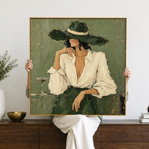 May include: A square framed oil painting depicting a person wearing a wide-brimmed dark green hat and a white long-sleeved shirt. The figure is seated, resting one hand on a table next to a martini glass. The background is a textured olive green.