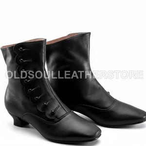 Op de afbeelding: Zwarte leren enkellaarsjes met een spitse neus en kleine hak. De laarzen hebben een geschulpte rand met knoopsluitingen. De tekst "OLDSOULEATHERSTORE" is zichtbaar op de laarzen.