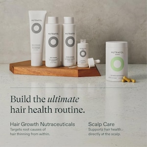 May include: A collection of white NUTRAFOL hair health products, including a tube, bottles, and a jar with capsules, arranged on a wooden surface. The products feature a circular design and the text "NUTRAFOL". The image also includes the text "Build the ultimate hair health routine."