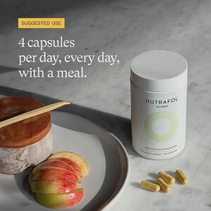 May include: A white cylindrical bottle of Nutrafol Women hair growth nutraceuticals with a light green design. The image also shows four capsules, sliced apples, and text that reads "4 capsules per day, every day, with a meal."