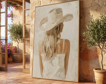 May include: An abstract painting depicting a person wearing a cowboy hat and a white dress, seen from behind. The artwork uses a neutral colour palette with beige, cream, and brown tones. The painting is displayed in a gold frame.