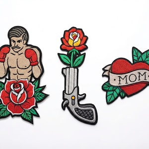 Può includere: Set di tre toppe ricamate con classici disegni di tatuaggi. Include un pugile con guantoni rossi e una rosa, una pistola con una rosa e un cuore con uno striscione "MOM".